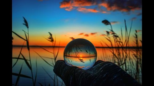 Creative crystal lens ball photography of a lake with greenery around at dawn