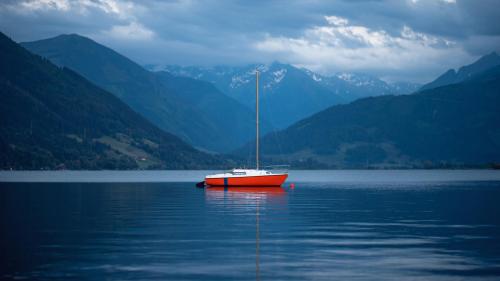 A Red Boat on Body of Water Near Mountains