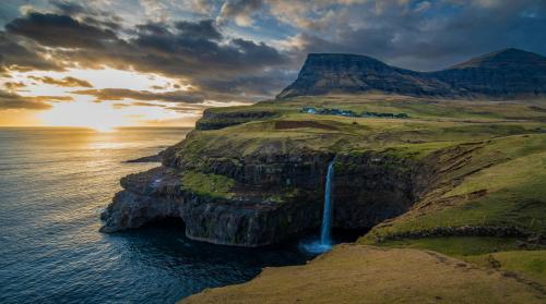 Múlafossur Waterfall plunging into the North Atlantic at sunset, Gásadalur, Faroe Islands