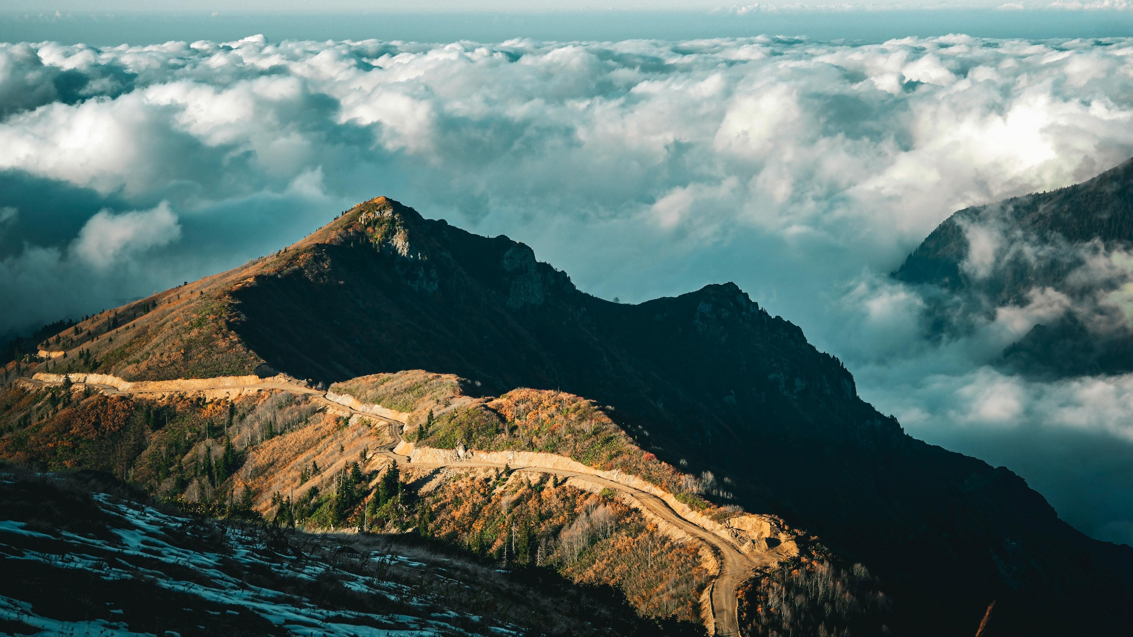 Mountain road above clouds with dramatic sunlight and scenic landscape view