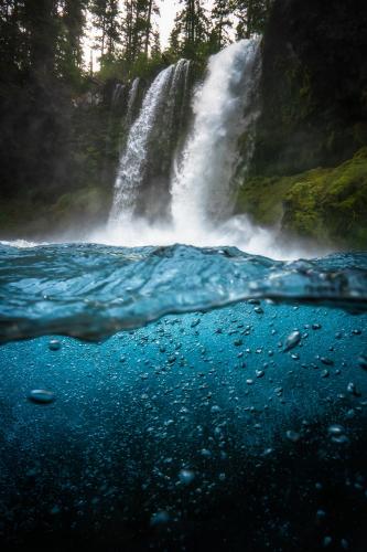 A partially underwater photo of a waterfall in Central Oregon.