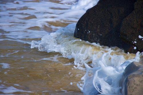 Sea water splashing against rocks on a beach in Norfolk, UK