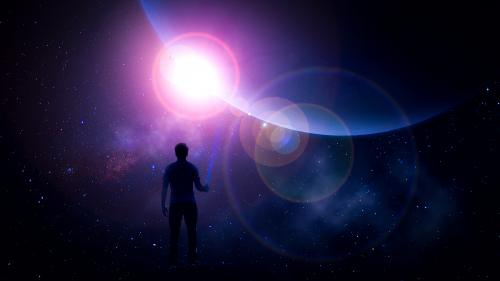 A man standing on a rock looking up at the dark sky. In the sky there is a giant planet shielding the camera from the sun. The sun is only slightly visible, creating a huge lens flare.