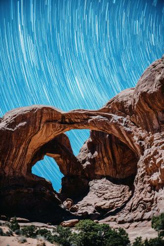 Star trail over the Double Arch illuminated by a quarter moon in Arches National Park, Utah.