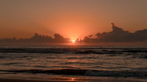 waves crashing on seashore during sunset