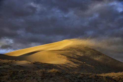 Wind at sunset creates blowing sand at the Kelso Dunes in Mojave National Preserve, California.