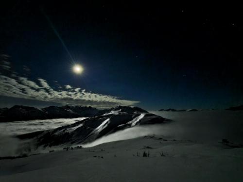 Fog cascades from one valley to another underneath the moon dappled mountains. Coastal mountains, BC, Canada.