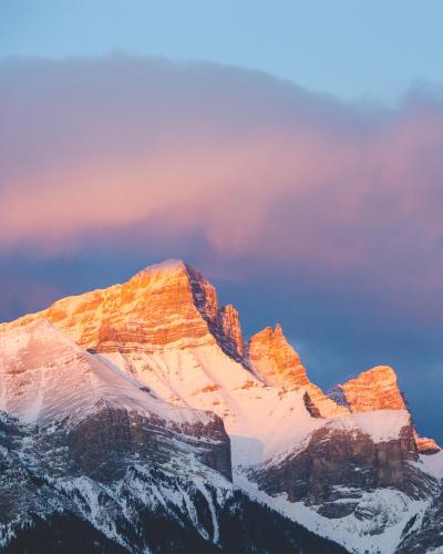 Gold light paints the mountain tops as the sun rises in Banff National Park
