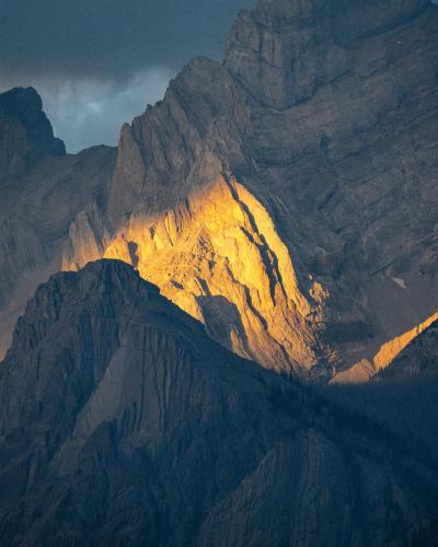 A sun beam breaks through the clouds to illuminate the details of a mountain. Southern British Columbia